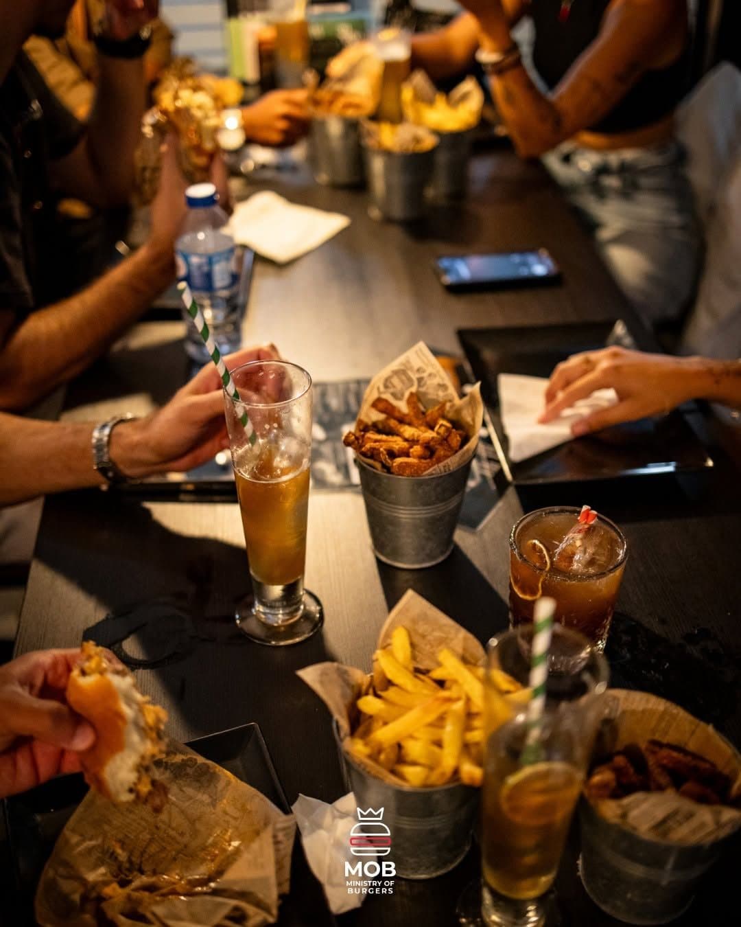 Mesa cheia de baldes de batatas, molhos e bebidas a ser partilhada
